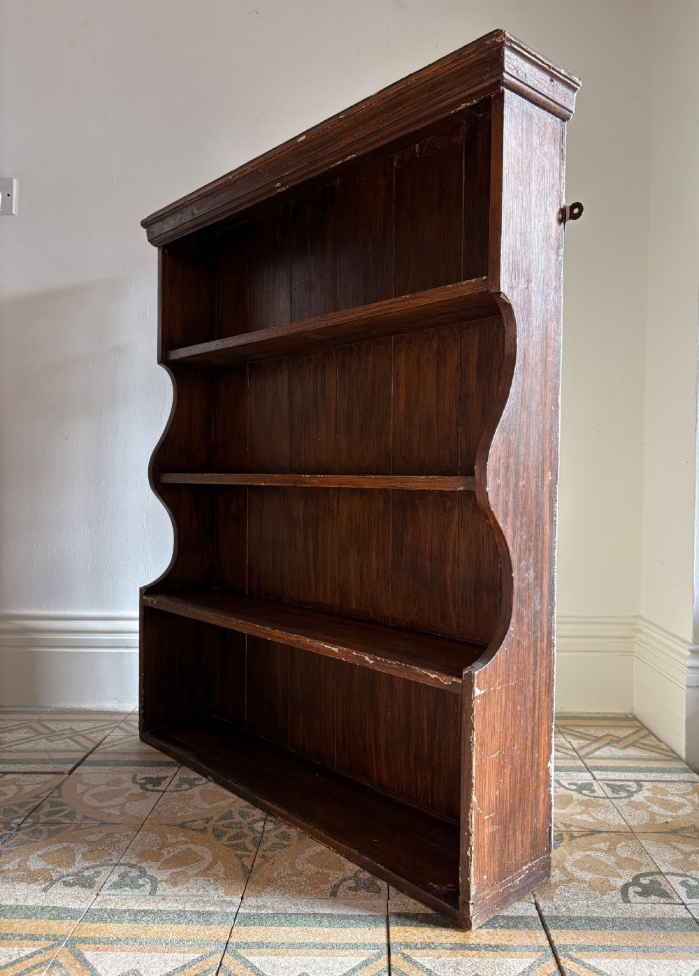 A 19th-century dark brown painted pine waterfall shelving unit featuring four open graduated shelves with curved sides. View IV