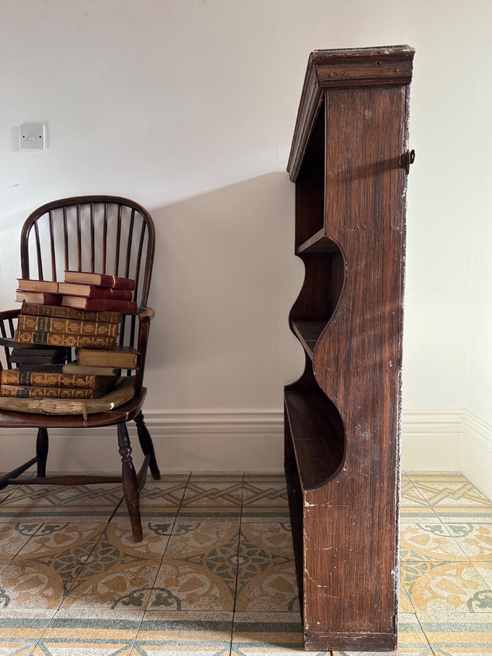 A 19th-century dark brown painted pine waterfall shelving unit featuring four open graduated shelves with curved sides. View V