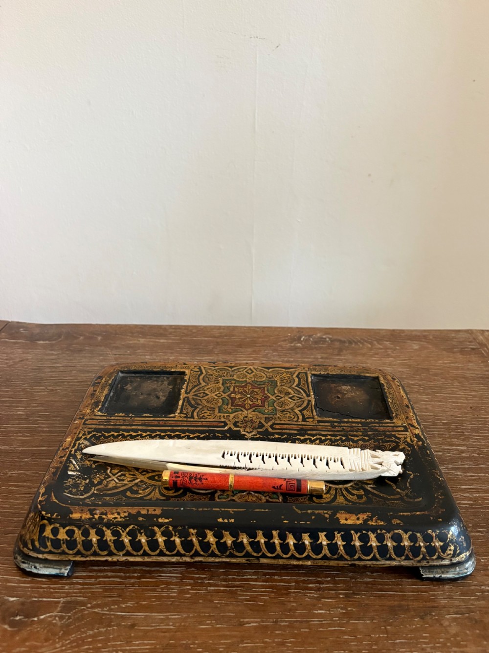 A rectangular hand-painted black and gold Kashmiri papier-mache inkstand featuring two square inkwell recesses and a long pen tray. View XI