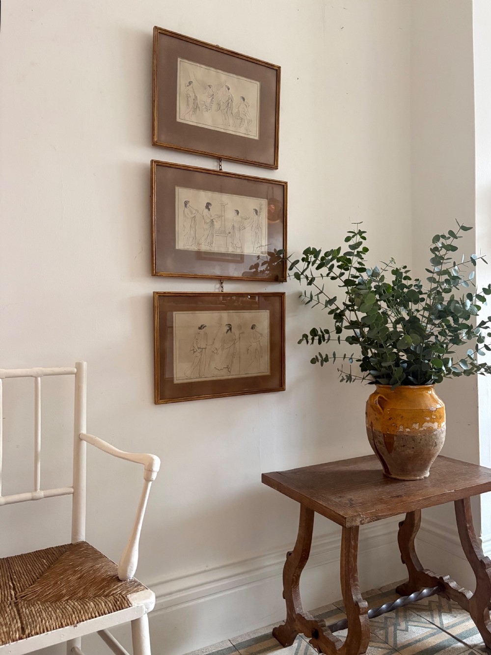 A vertical set of three framed Neoclassical line illustrations depicting classical figures from Homers Odyssey, linked together by small metal rings on a white wall. View XIII