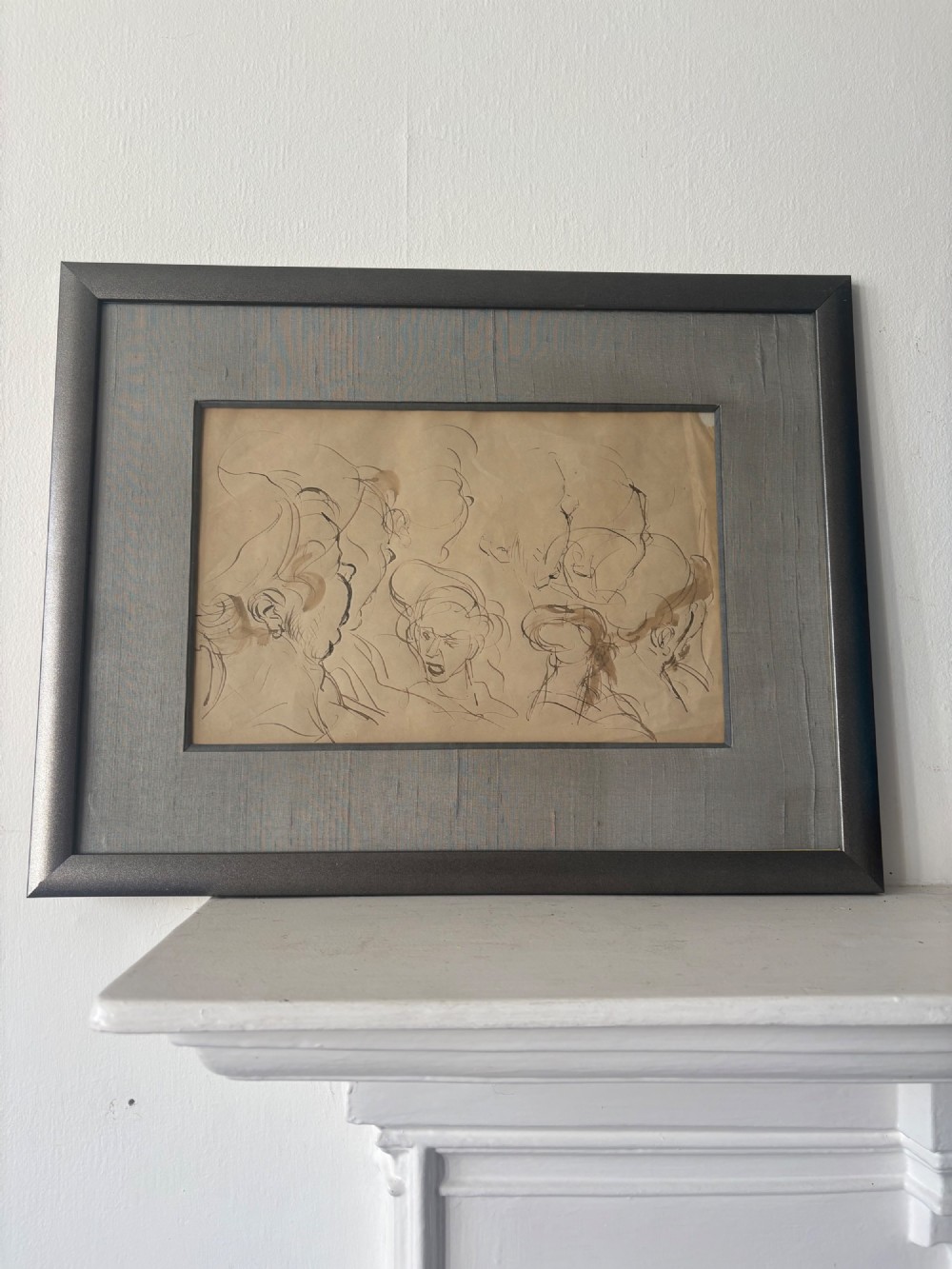 A framed 19th-century sepia pen and ink preparatory drawing depicting expressively sketched head studies on aged paper. View IV