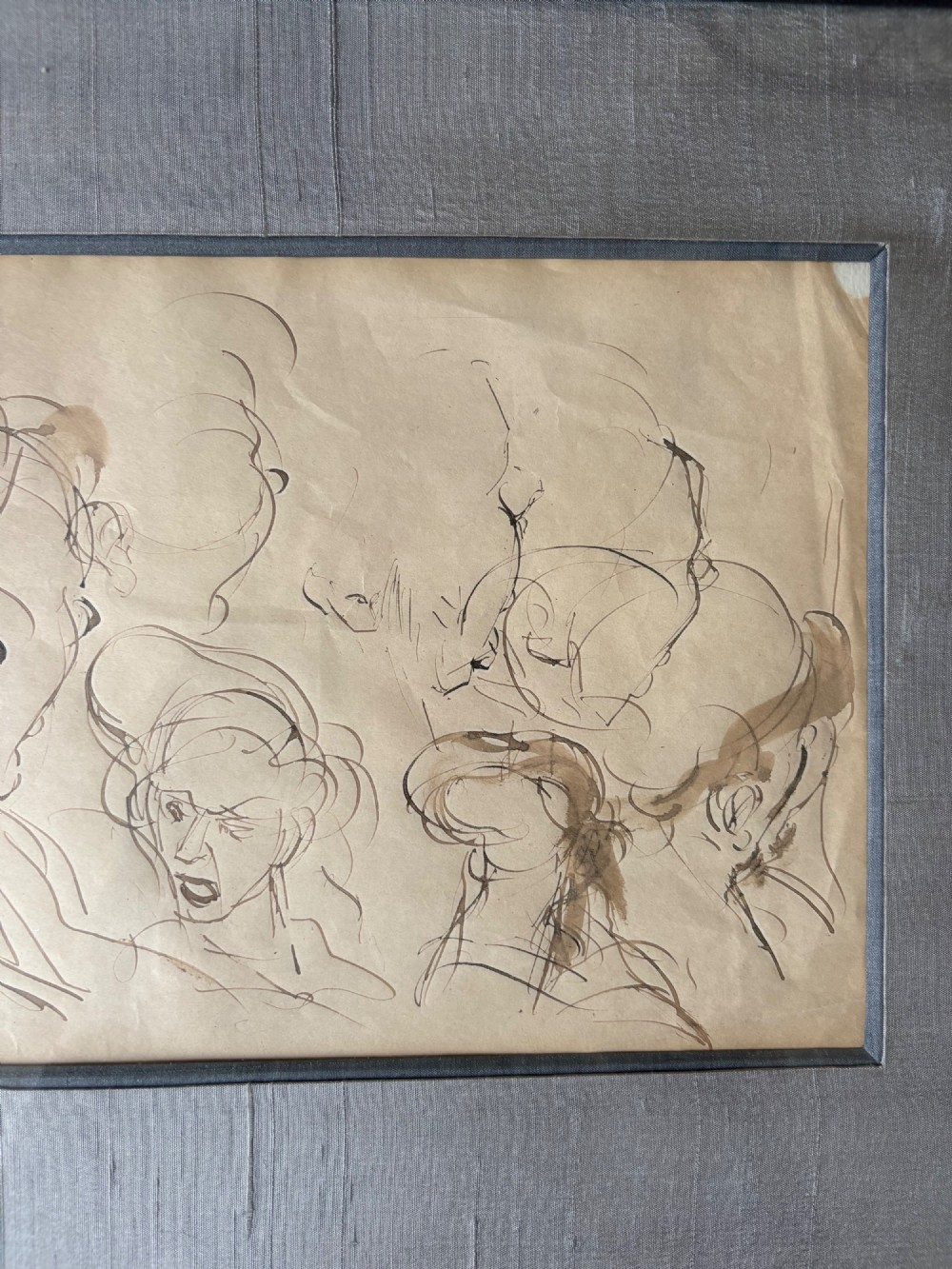 A framed 19th-century sepia pen and ink preparatory drawing depicting expressively sketched head studies on aged paper. View XIII