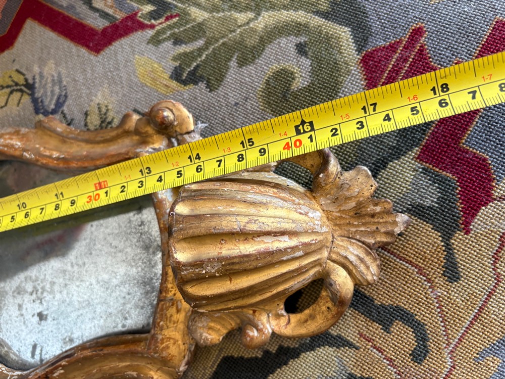 An 18th-century Italian Rococo carved giltwood cartouche wall mirror featuring ornate scrollwork, an upper crest, and a heavily foxed mirror glass plate. View XIII