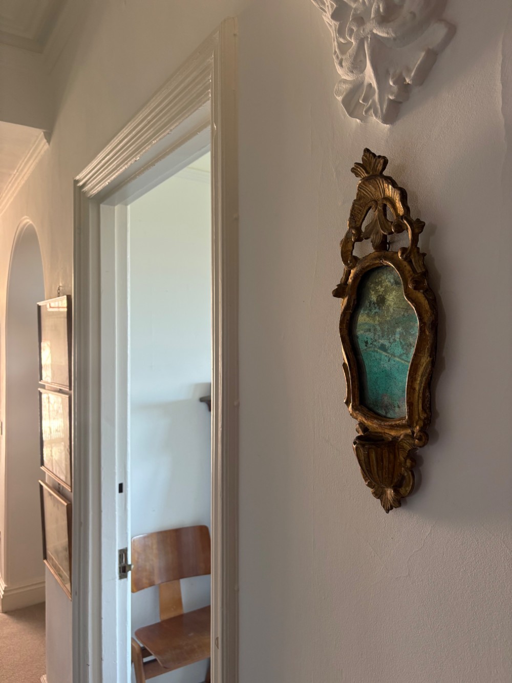 An 18th-century Italian Rococo carved giltwood cartouche wall mirror featuring ornate scrollwork, an upper crest, and a heavily foxed mirror glass plate. View XV