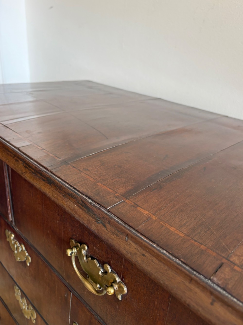 A mid-18th-century Georgian walnut chest of drawers featuring a two-over-three drawer layout, brass handles with backplates, and bracket feet. View III