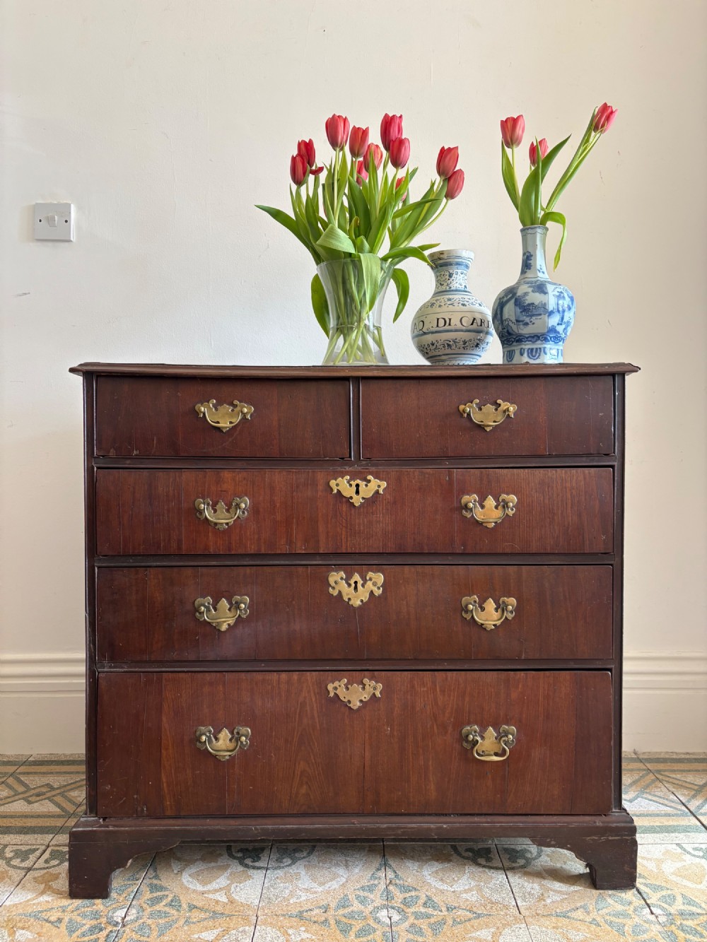 A mid-18th-century Georgian walnut chest of drawers featuring a two-over-three drawer layout, brass handles with backplates, and bracket feet. View V