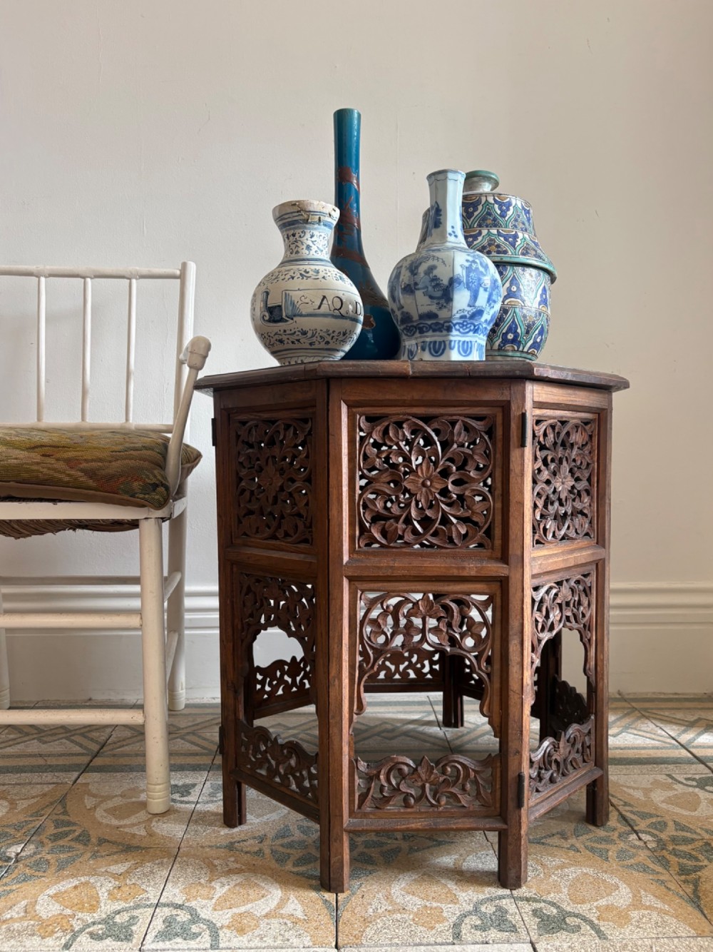 An octagonal dark teak side table featuring intricate openwork floral carving and arched fretwork base panels. View II