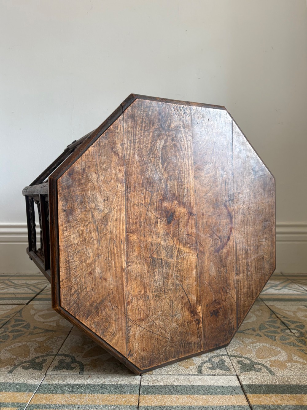 An octagonal dark teak side table featuring intricate openwork floral carving and arched fretwork base panels. View III
