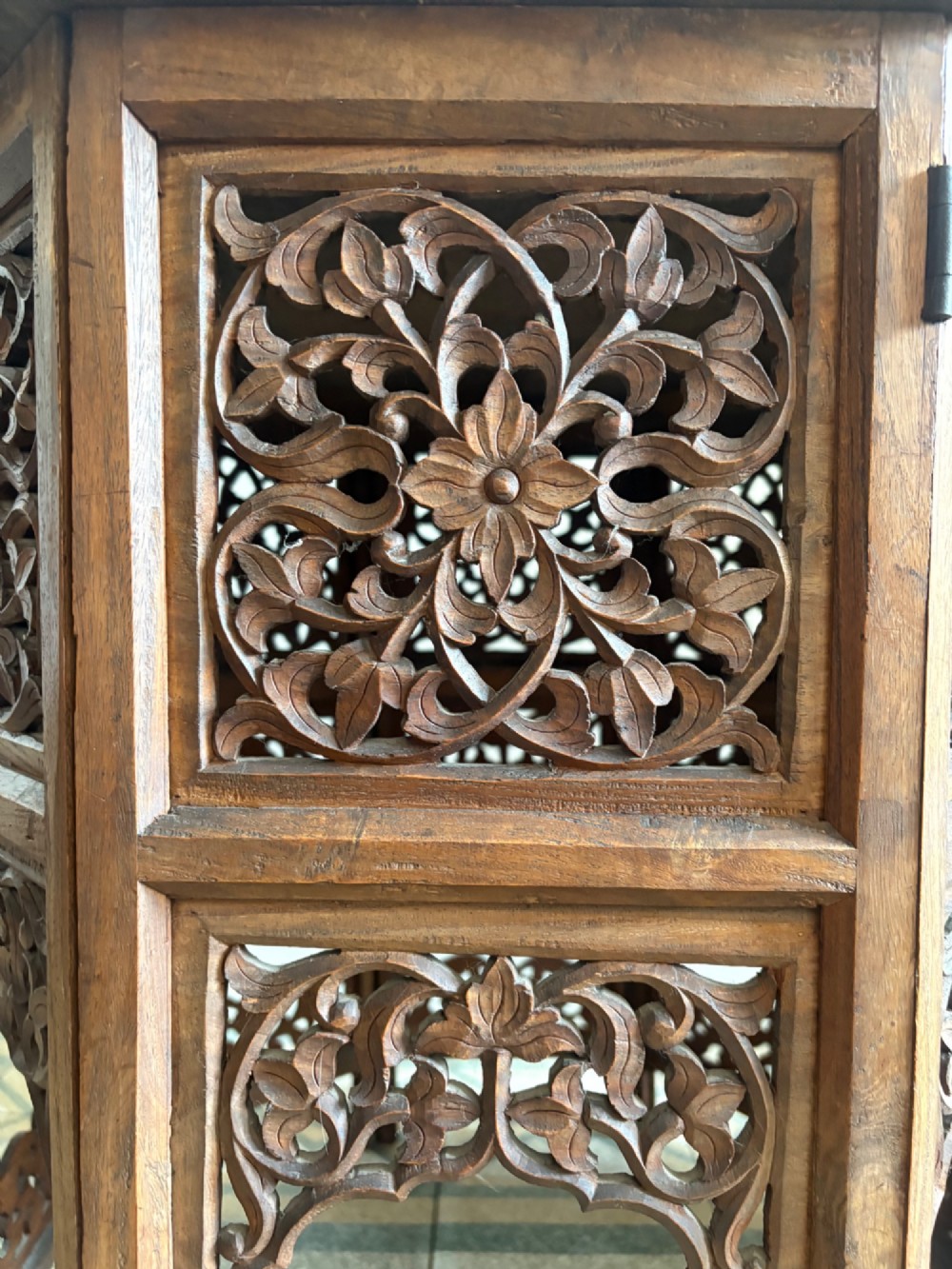 An octagonal dark teak side table featuring intricate openwork floral carving and arched fretwork base panels. View V