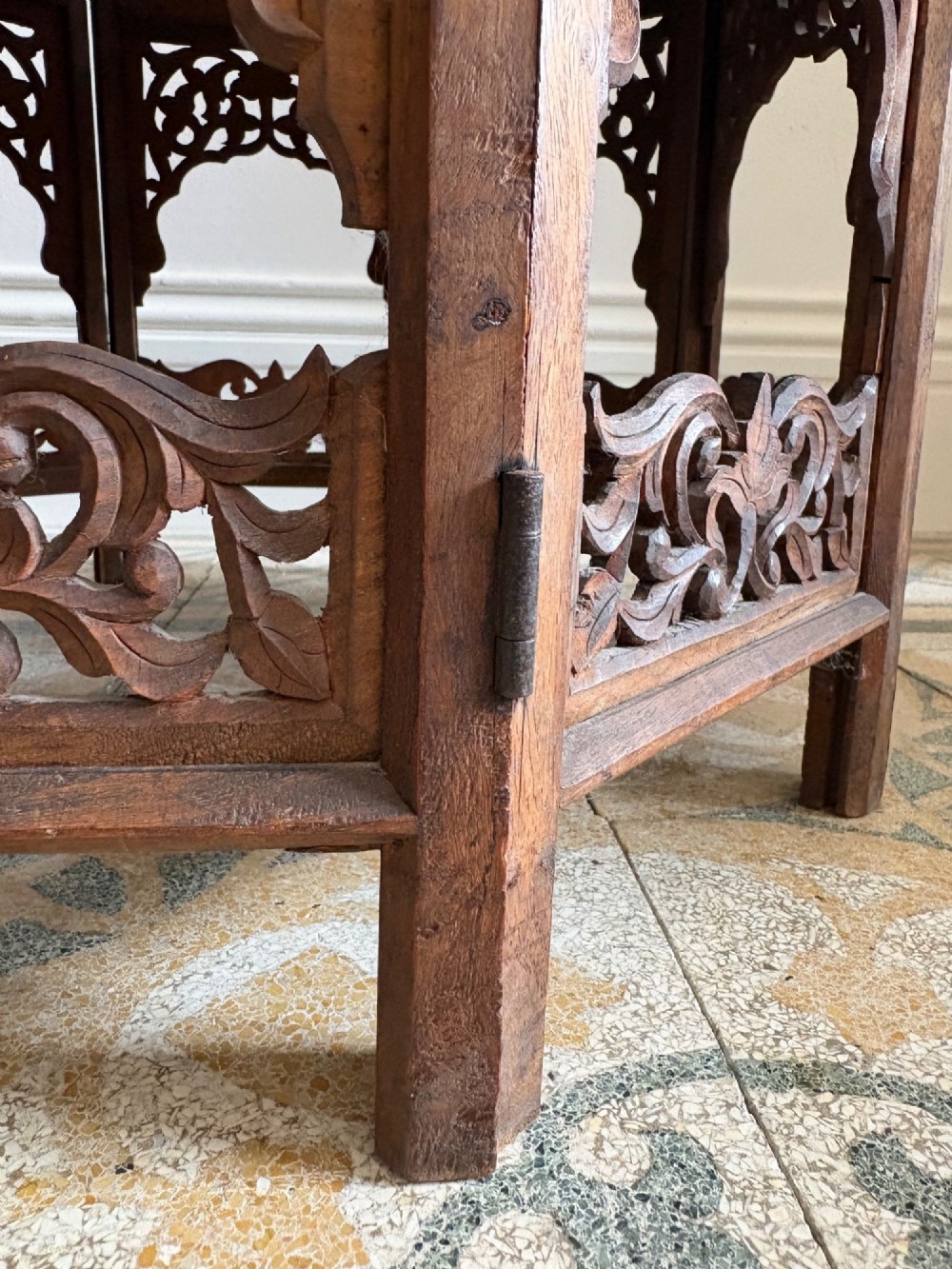 An octagonal dark teak side table featuring intricate openwork floral carving and arched fretwork base panels. View VII