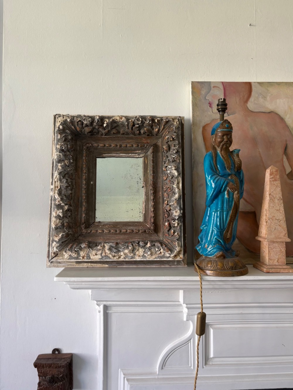 A small rectangular dark wood frame with heavily textured gesso carving enclosing a foxed mirror plate. View IV