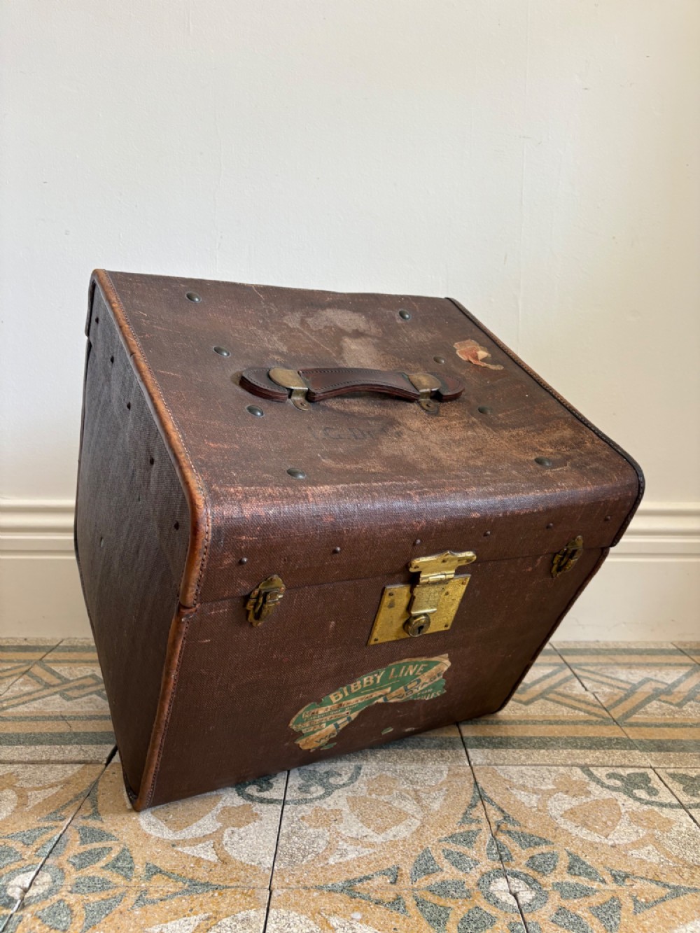 An Edwardian brown canvas and leather hat box trunk featuring brass latches, stitched leather trim, and an ocean liner travel label on the front. View II