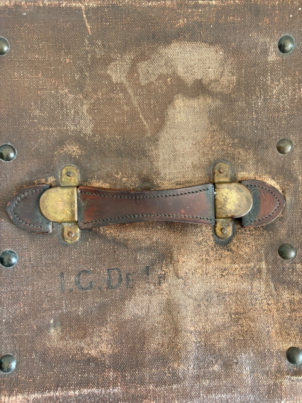 An Edwardian brown canvas and leather hat box trunk featuring brass latches, stitched leather trim, and an ocean liner travel label on the front. View V