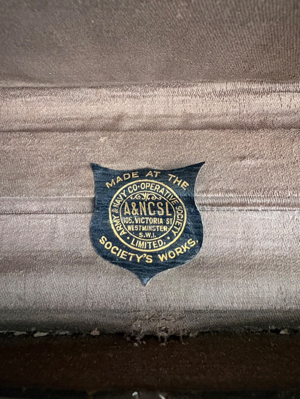 An Edwardian brown canvas and leather hat box trunk featuring brass latches, stitched leather trim, and an ocean liner travel label on the front. View VII