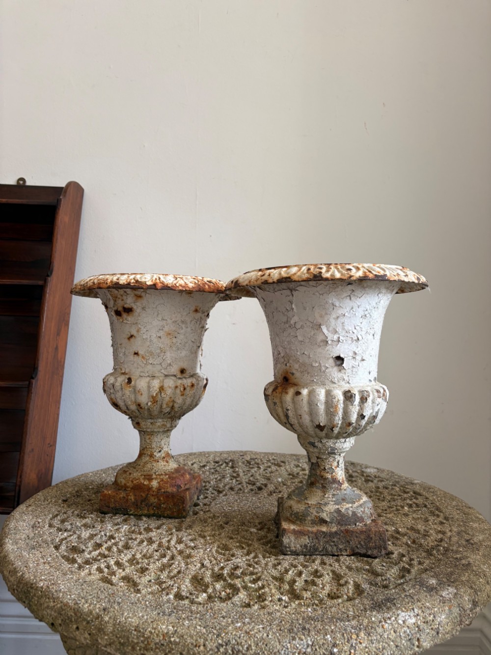 A pair of 19th-century classical cast iron garden urns featuring distressed flaking white paint, fluted bowls, and square bases. View IV