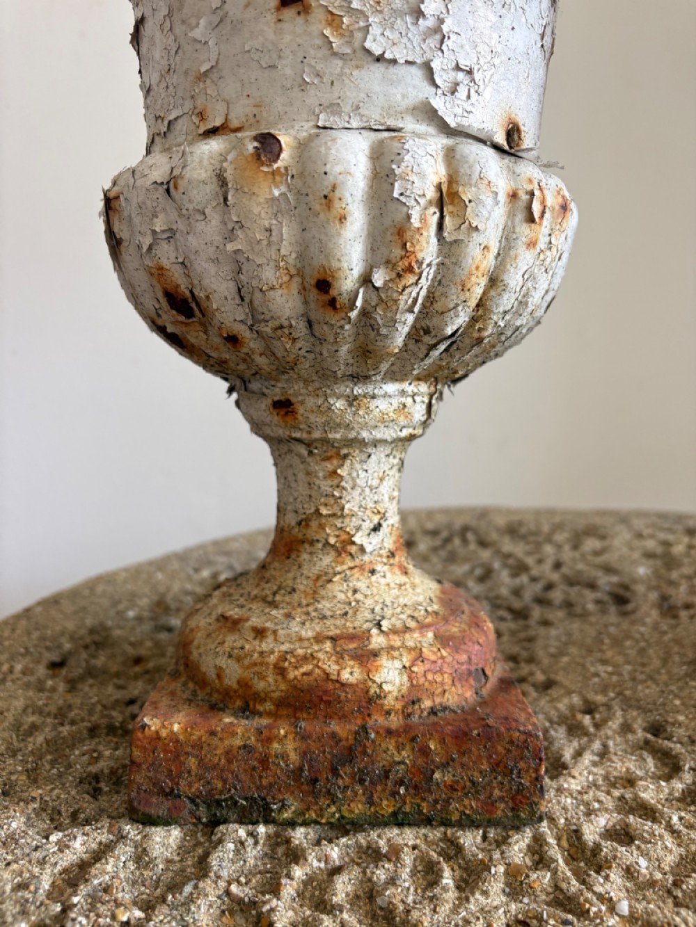 A pair of 19th-century classical cast iron garden urns featuring distressed flaking white paint, fluted bowls, and square bases. View VII