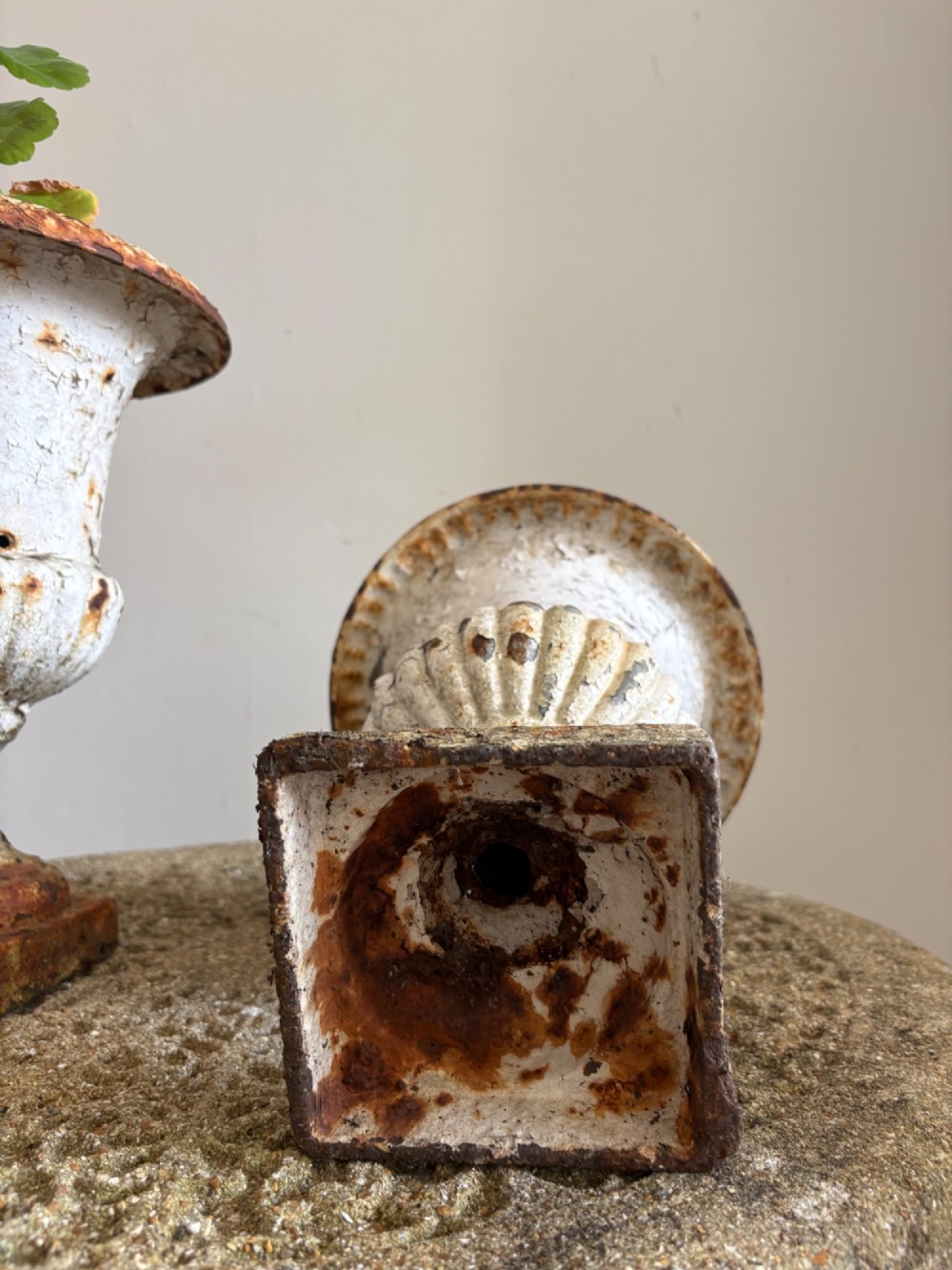 A pair of 19th-century classical cast iron garden urns featuring distressed flaking white paint, fluted bowls, and square bases. View X