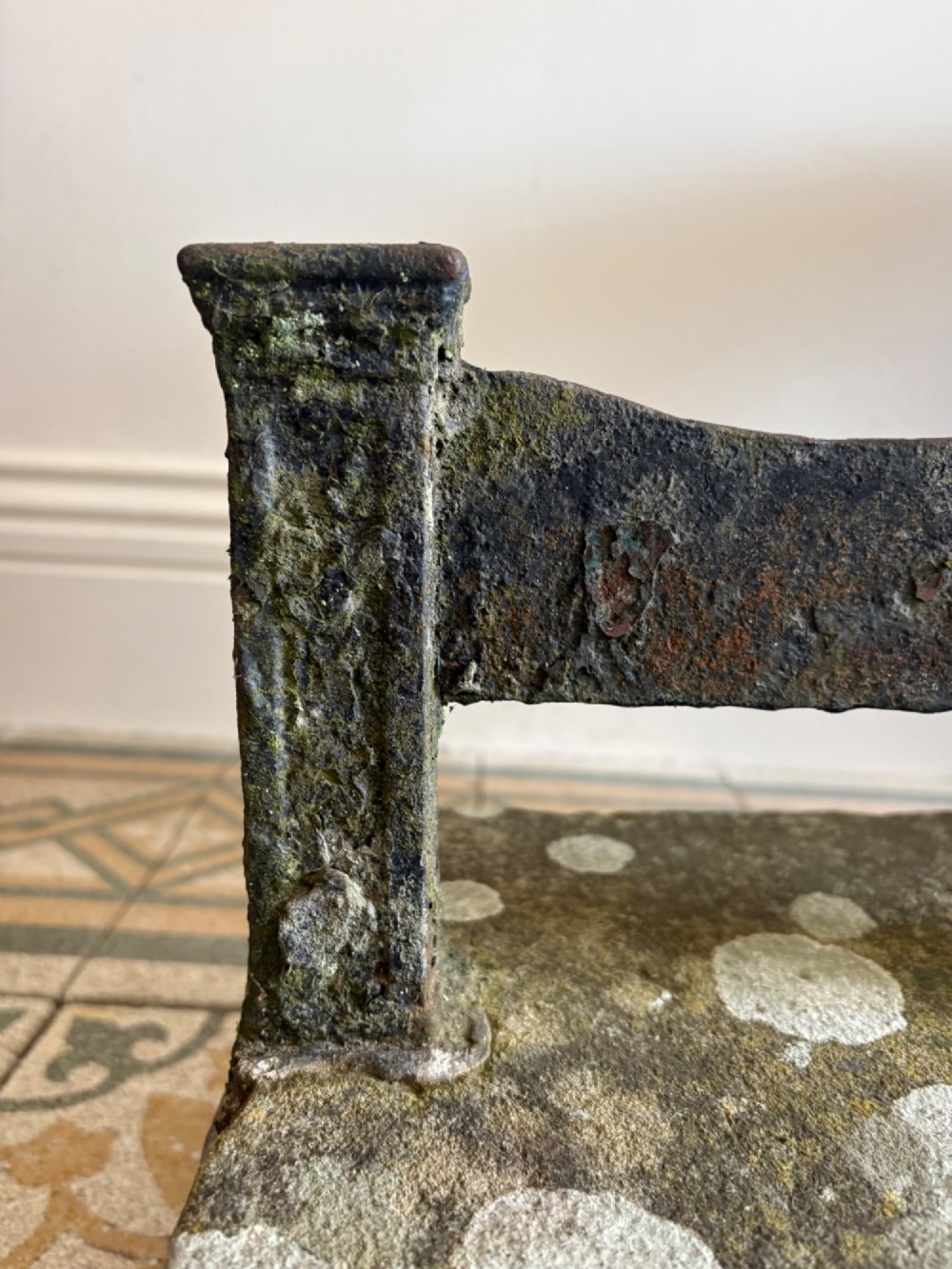 A 19th-century cast iron boot scraper with a central scraping blade set between two vertical pillars, mounted into a heavy hand-hewn stone block. View II