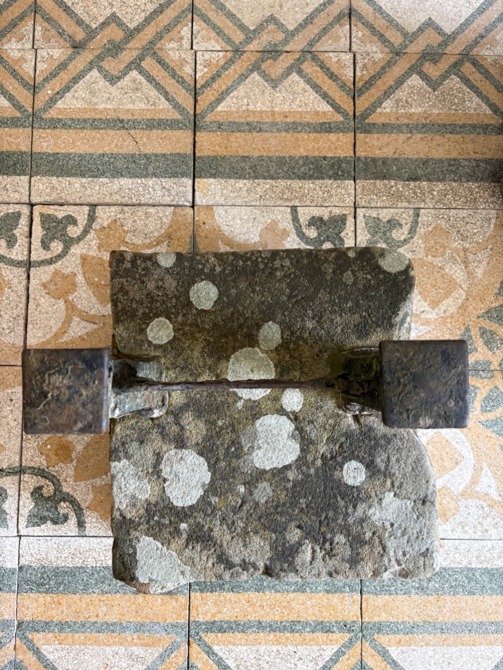 A 19th-century cast iron boot scraper with a central scraping blade set between two vertical pillars, mounted into a heavy hand-hewn stone block. View III