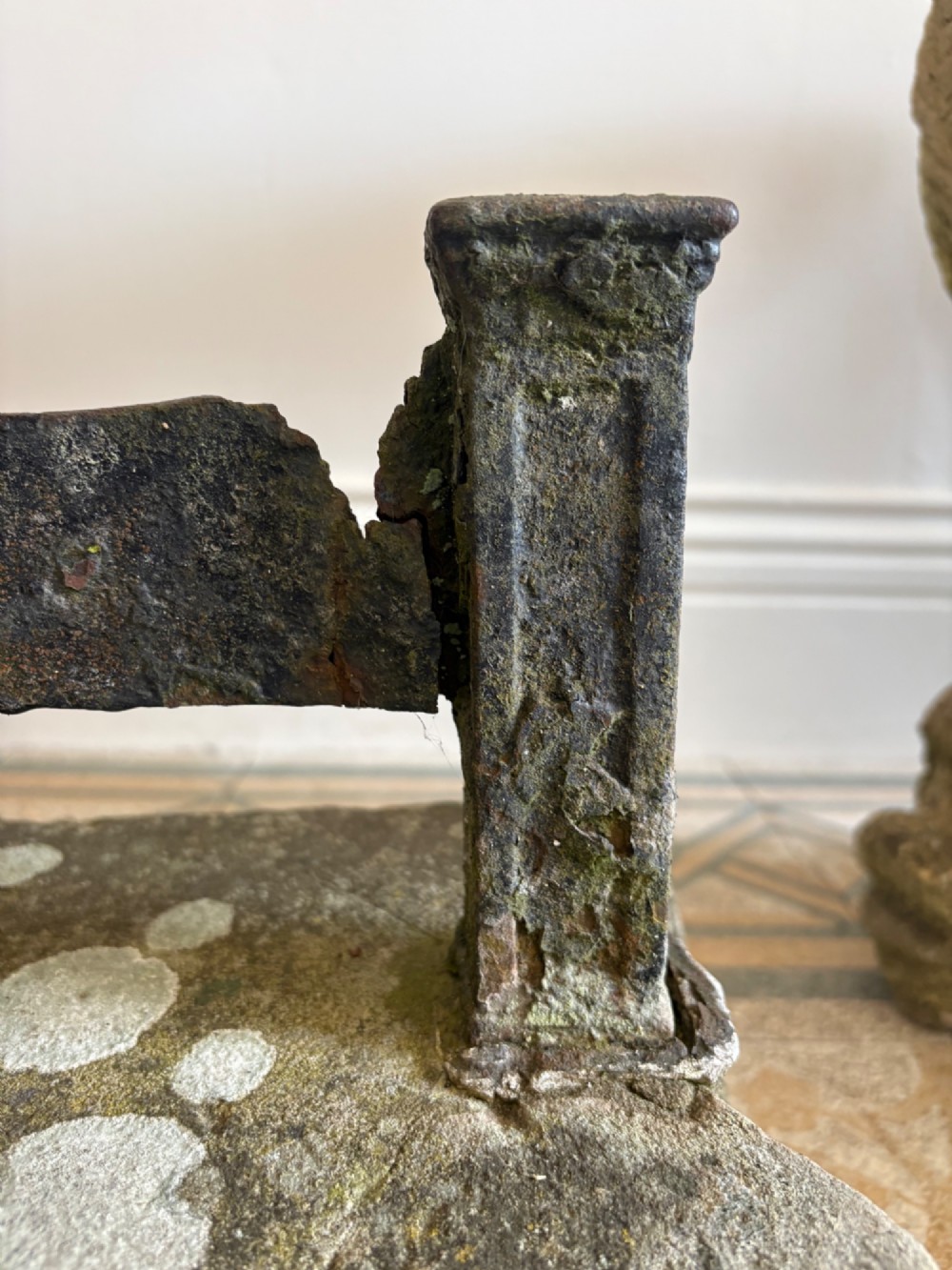 A 19th-century cast iron boot scraper with a central scraping blade set between two vertical pillars, mounted into a heavy hand-hewn stone block. View V