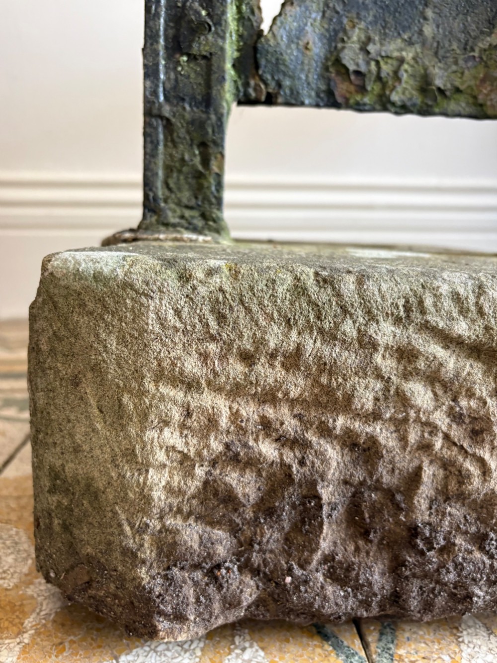 A 19th-century cast iron boot scraper with a central scraping blade set between two vertical pillars, mounted into a heavy hand-hewn stone block. View X