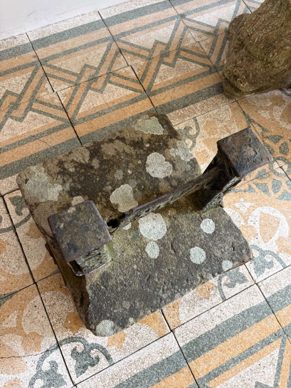 A 19th-century cast iron boot scraper with a central scraping blade set between two vertical pillars, mounted into a heavy hand-hewn stone block. View XI
