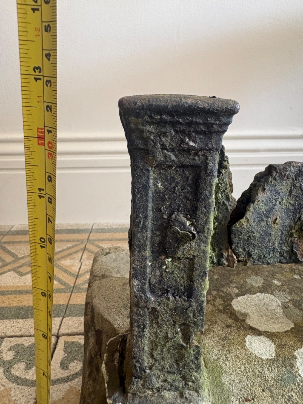 A 19th-century cast iron boot scraper with a central scraping blade set between two vertical pillars, mounted into a heavy hand-hewn stone block. View XII