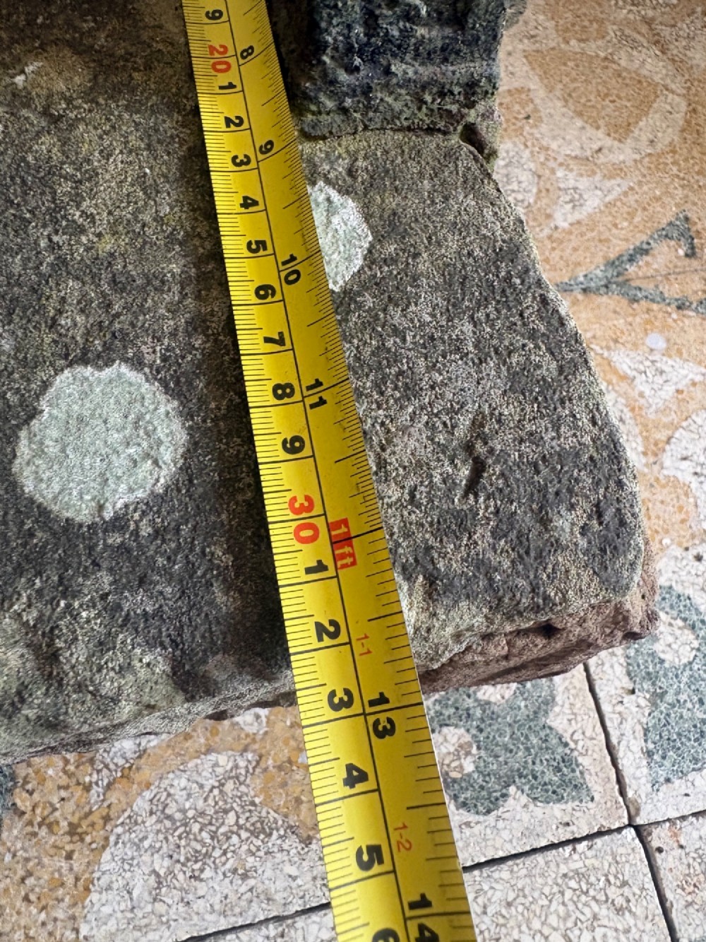 A 19th-century cast iron boot scraper with a central scraping blade set between two vertical pillars, mounted into a heavy hand-hewn stone block. View XIII