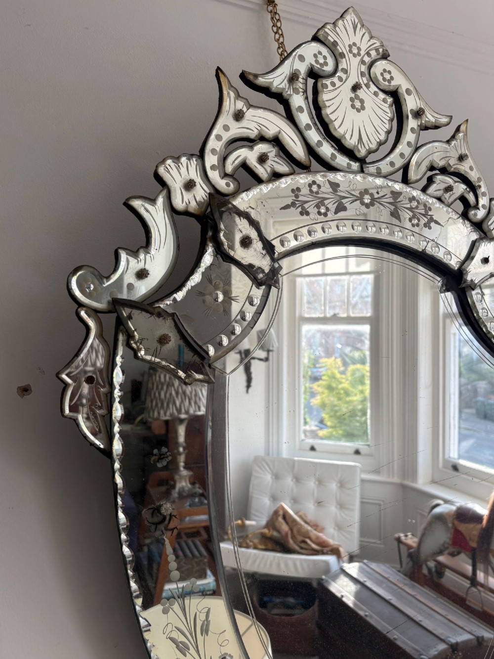 An oval Venetian wall mirror featuring an etched glass frame with floral motifs, a scrollwork crest, and a bevelled centre mirror with light foxing. View XIV