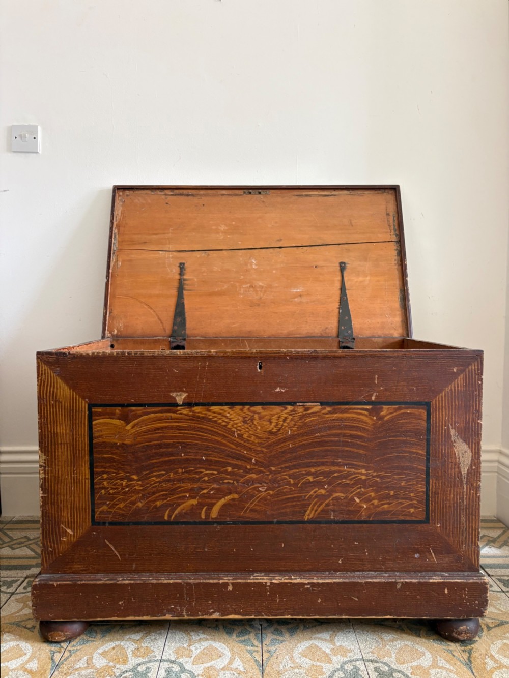 A 19th-century rectangular pine trunk featuring decorative scumble glazed painted panels, a hinged lid, and turned bun feet. View II