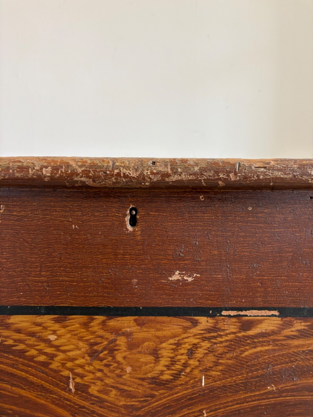 A 19th-century rectangular pine trunk featuring decorative scumble glazed painted panels, a hinged lid, and turned bun feet. View V
