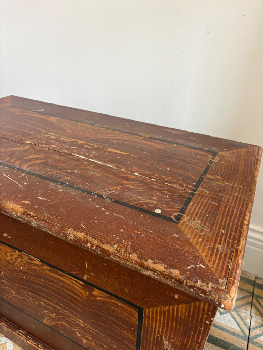 A 19th-century rectangular pine trunk featuring decorative scumble glazed painted panels, a hinged lid, and turned bun feet. View X