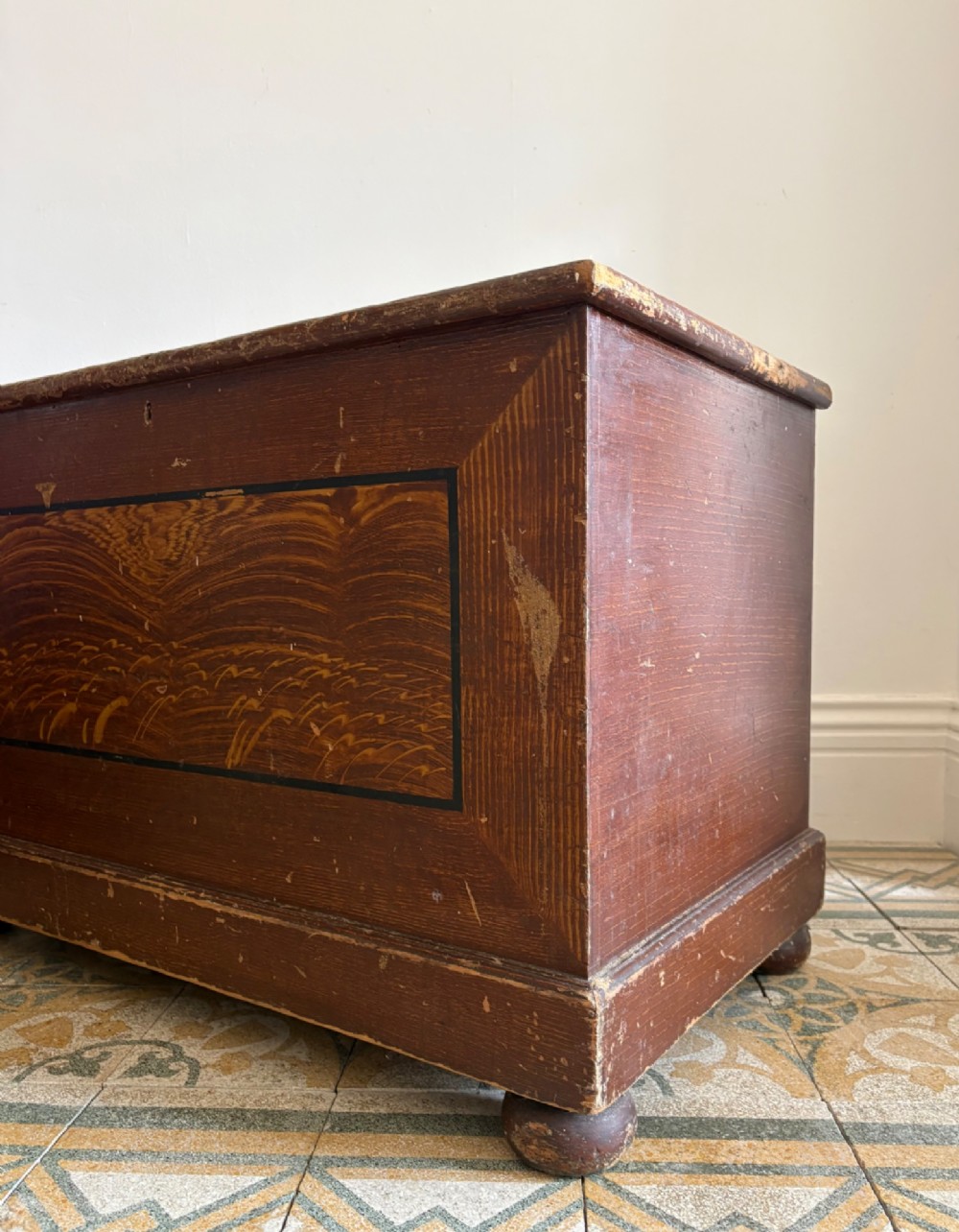 A 19th-century rectangular pine trunk featuring decorative scumble glazed painted panels, a hinged lid, and turned bun feet. View XI