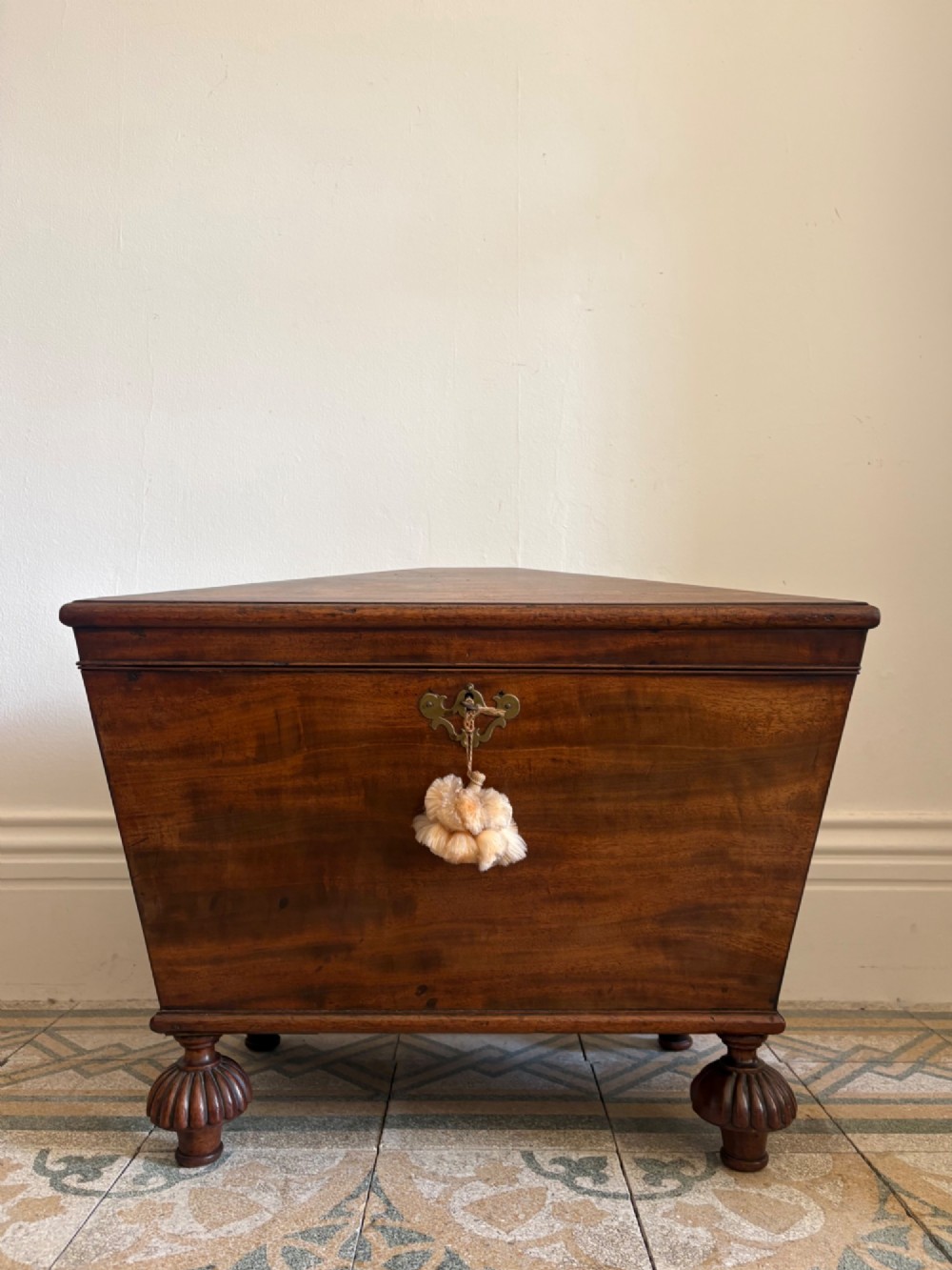 A Regency tapered mahogany sarcophagus cellarette featuring a hinged lid, keyhole with brass escutcheon, and turned gadrooned feet. View II