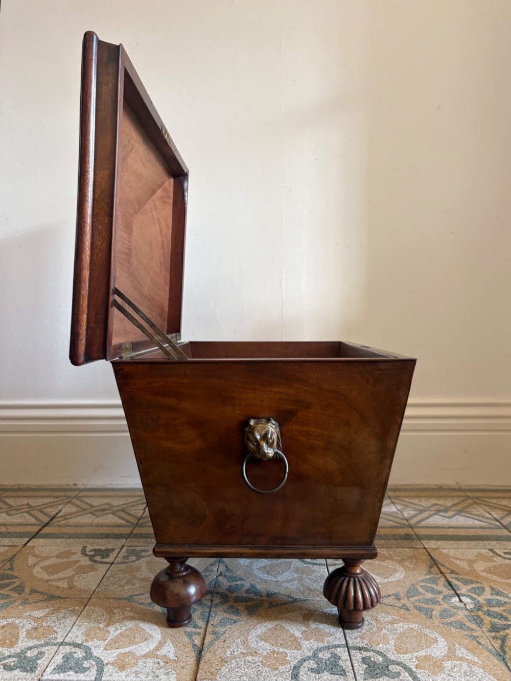 A Regency tapered mahogany sarcophagus cellarette featuring a hinged lid, keyhole with brass escutcheon, and turned gadrooned feet. View III