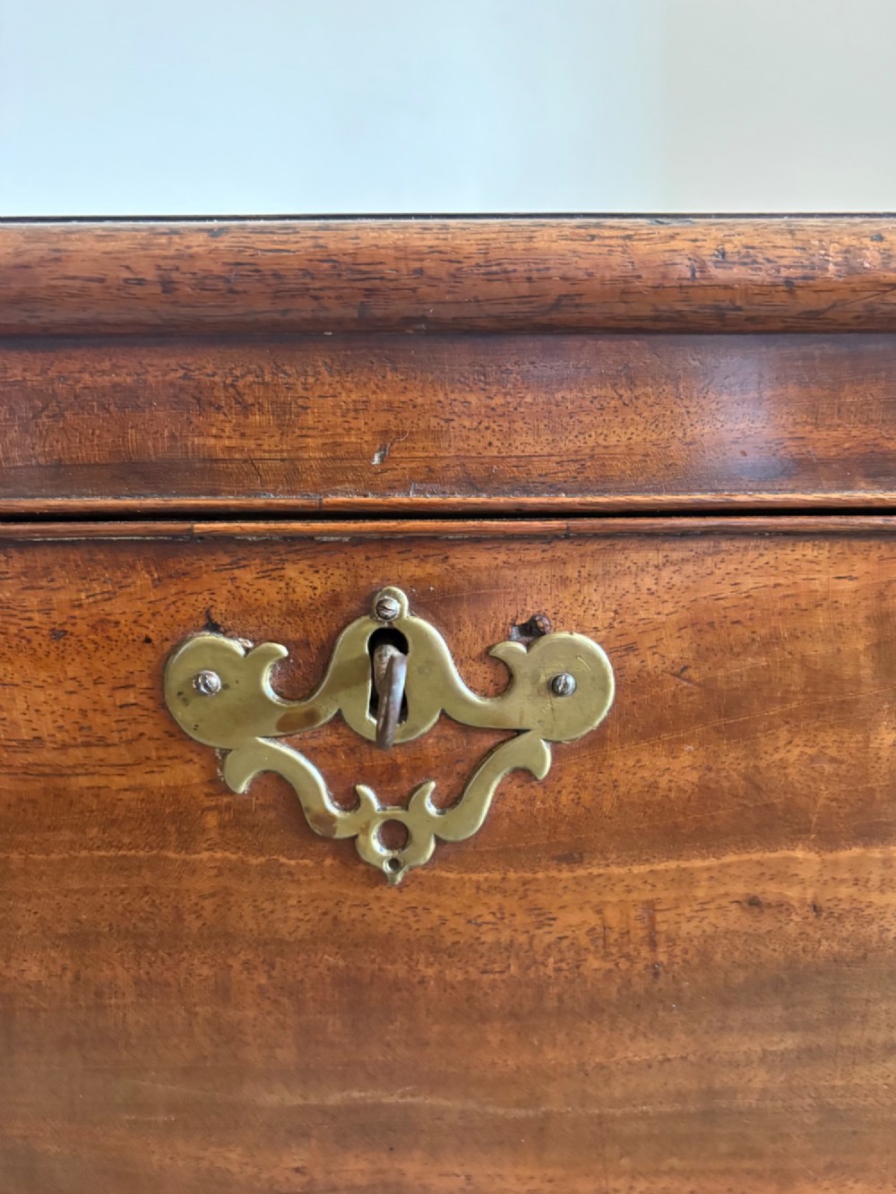A Regency tapered mahogany sarcophagus cellarette featuring a hinged lid, keyhole with brass escutcheon, and turned gadrooned feet. View XII