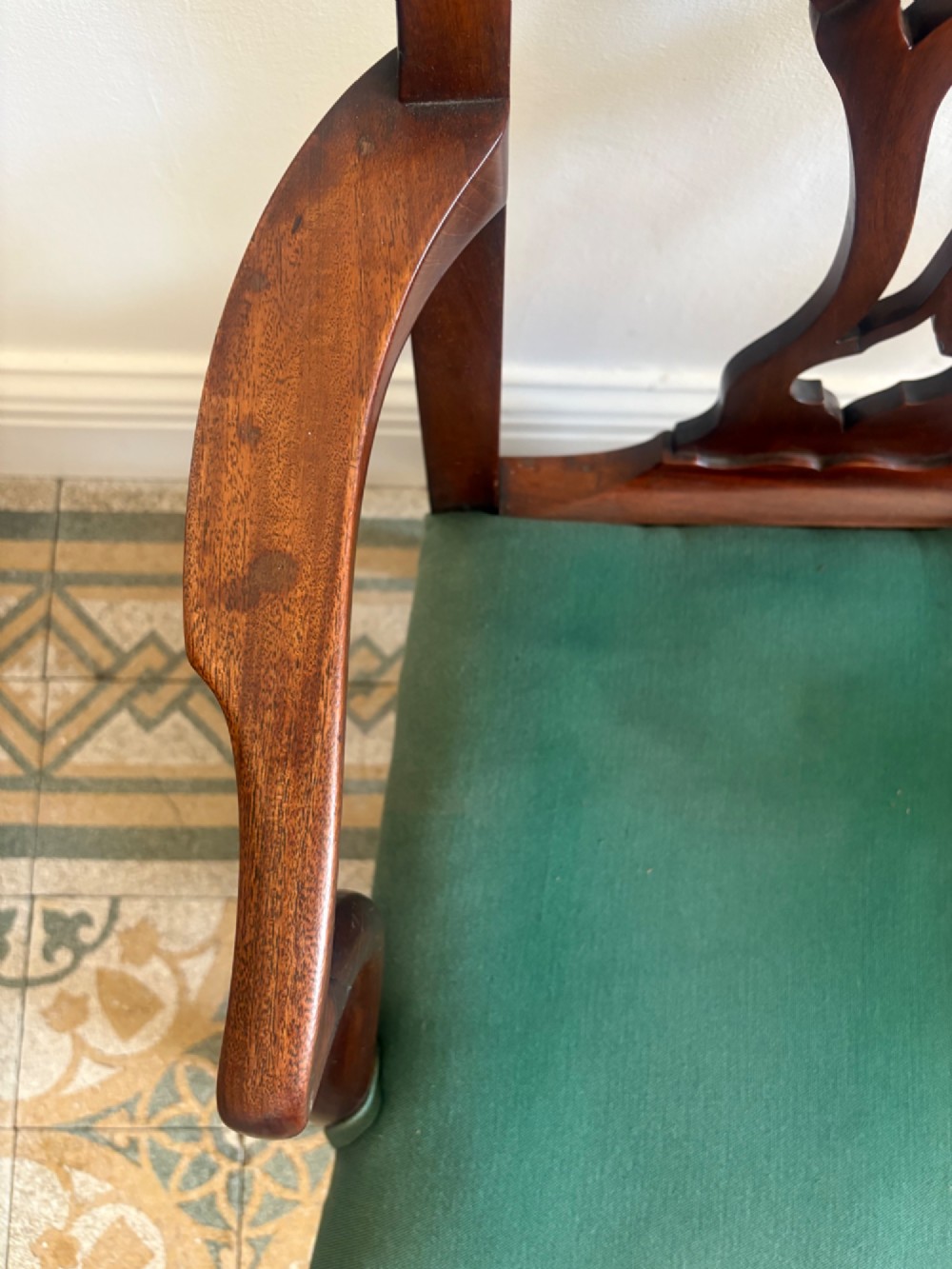 A George III mahogany elbow chair featuring a carved pierced splat back, swept armrests, and a green upholstered seat. View VI