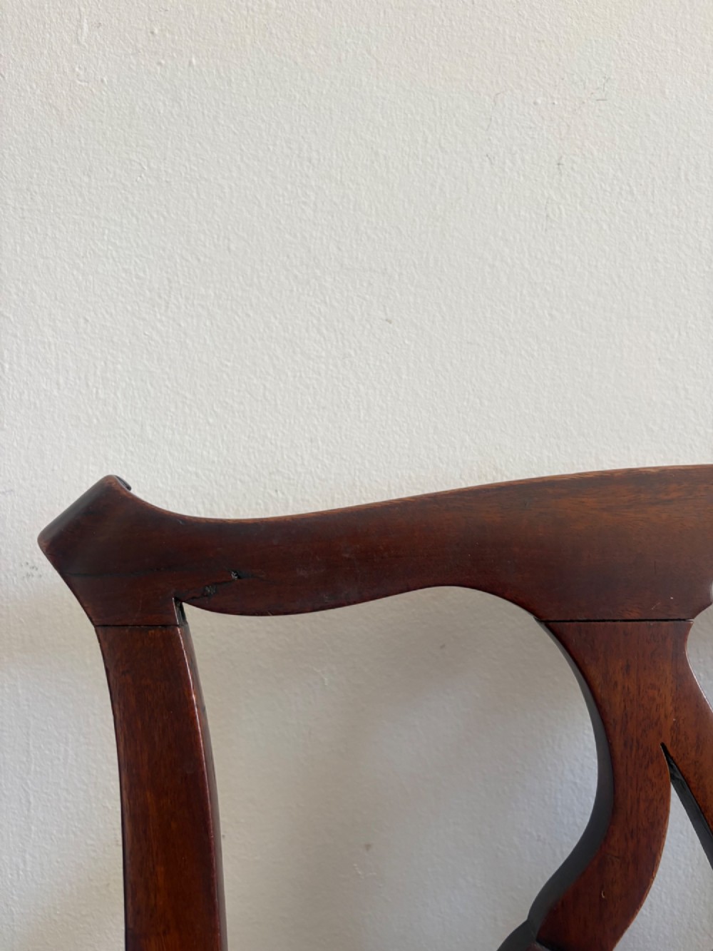 A George III mahogany elbow chair featuring a carved pierced splat back, swept armrests, and a green upholstered seat. View VII