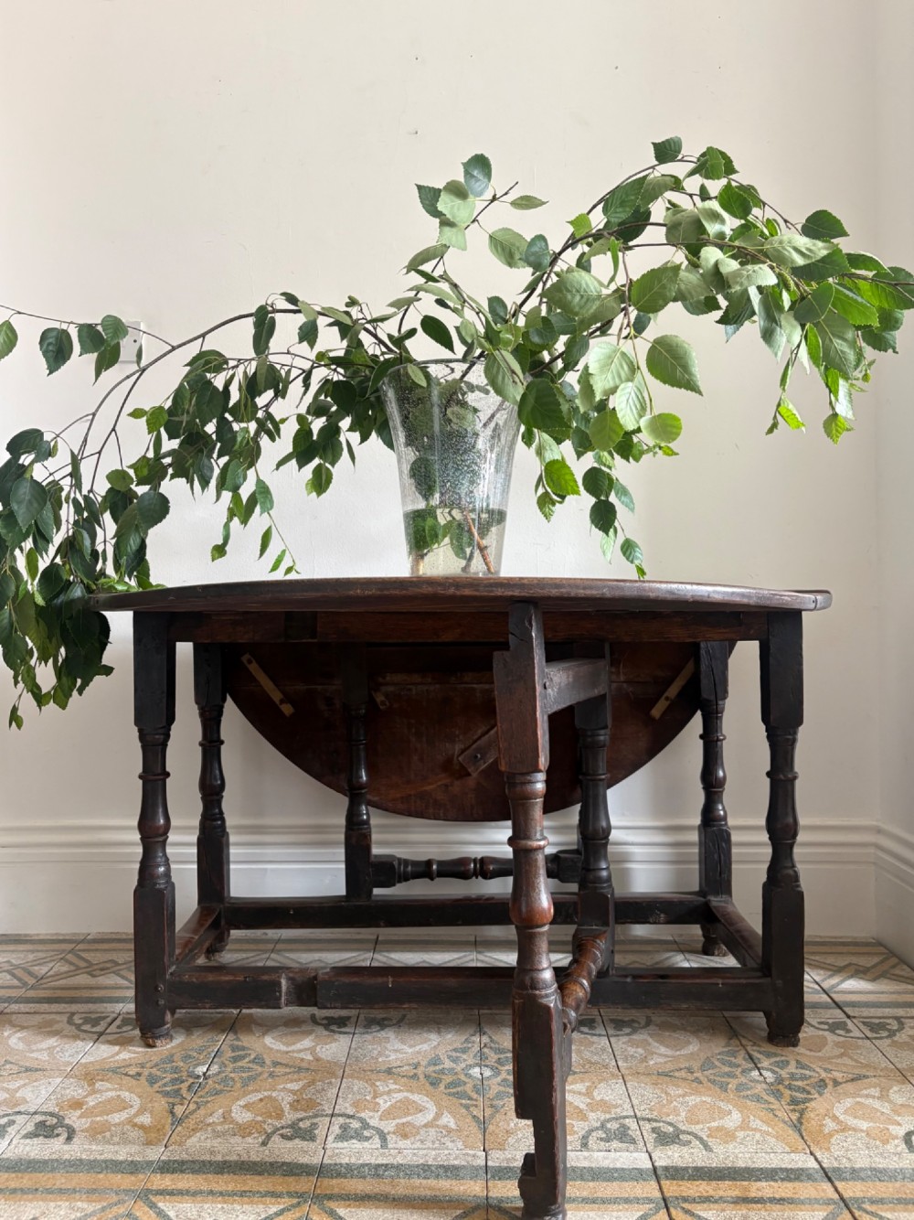 A dark oak gateleg table with a drop-leaf plank top and turned baluster legs joined by low stretchers. View IX