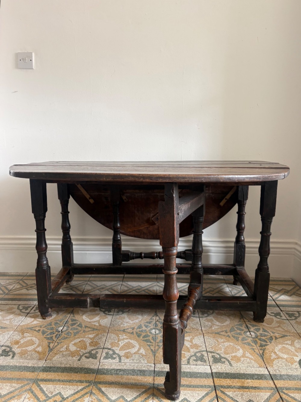 A dark oak gateleg table with a drop-leaf plank top and turned baluster legs joined by low stretchers. View X