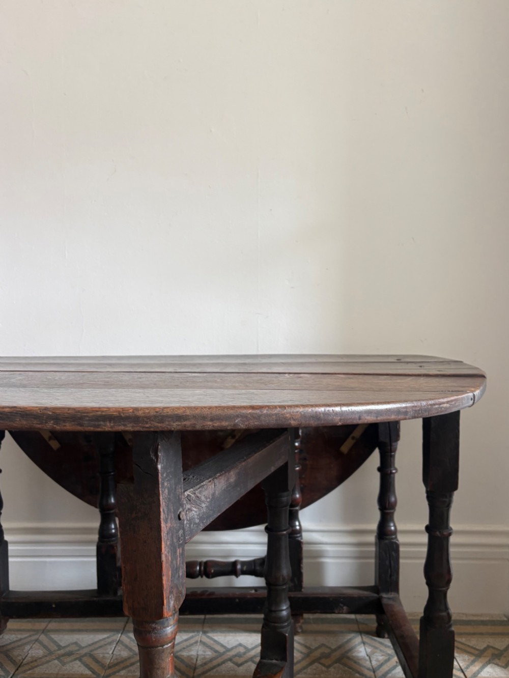 A dark oak gateleg table with a drop-leaf plank top and turned baluster legs joined by low stretchers. View XI