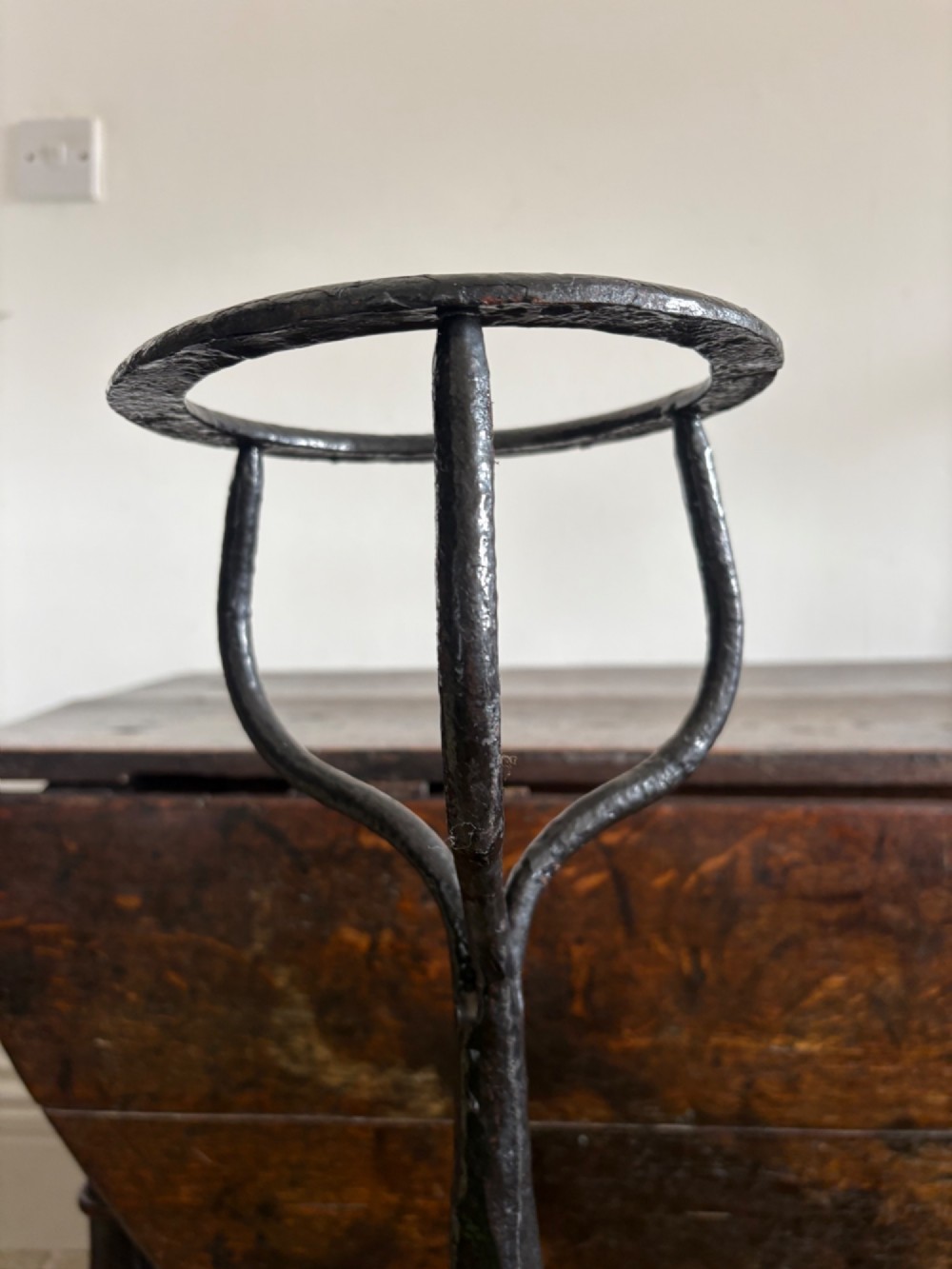 A pair of tall 19th-century black wrought iron fire dogs featuring hand-twisted shafts, scrollwork feet, and circular top ring terminals. View III