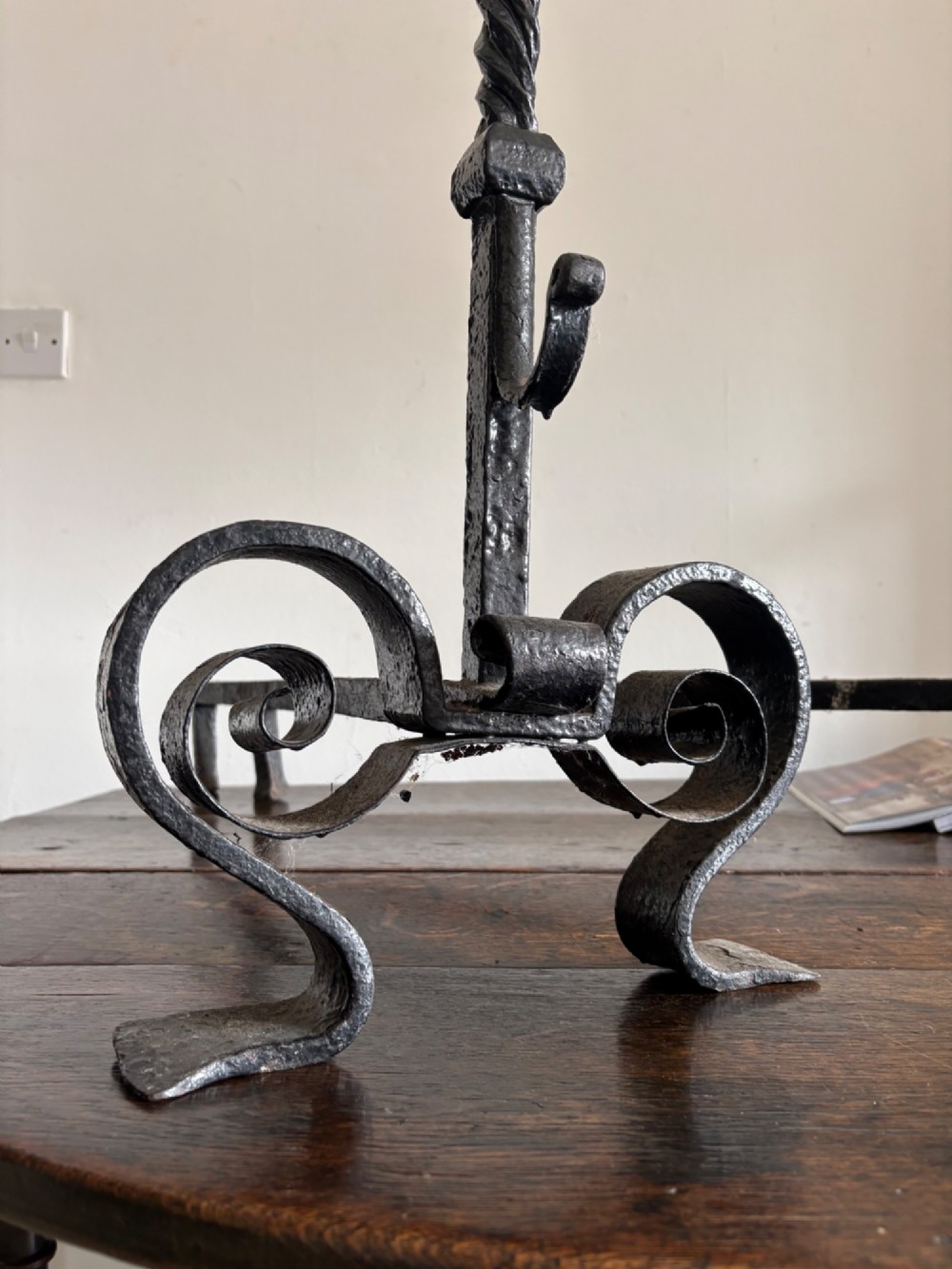 A pair of tall 19th-century black wrought iron fire dogs featuring hand-twisted shafts, scrollwork feet, and circular top ring terminals. View V