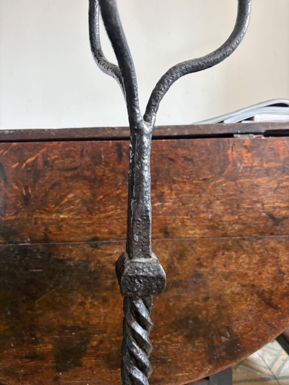 A pair of tall 19th-century black wrought iron fire dogs featuring hand-twisted shafts, scrollwork feet, and circular top ring terminals. View VI