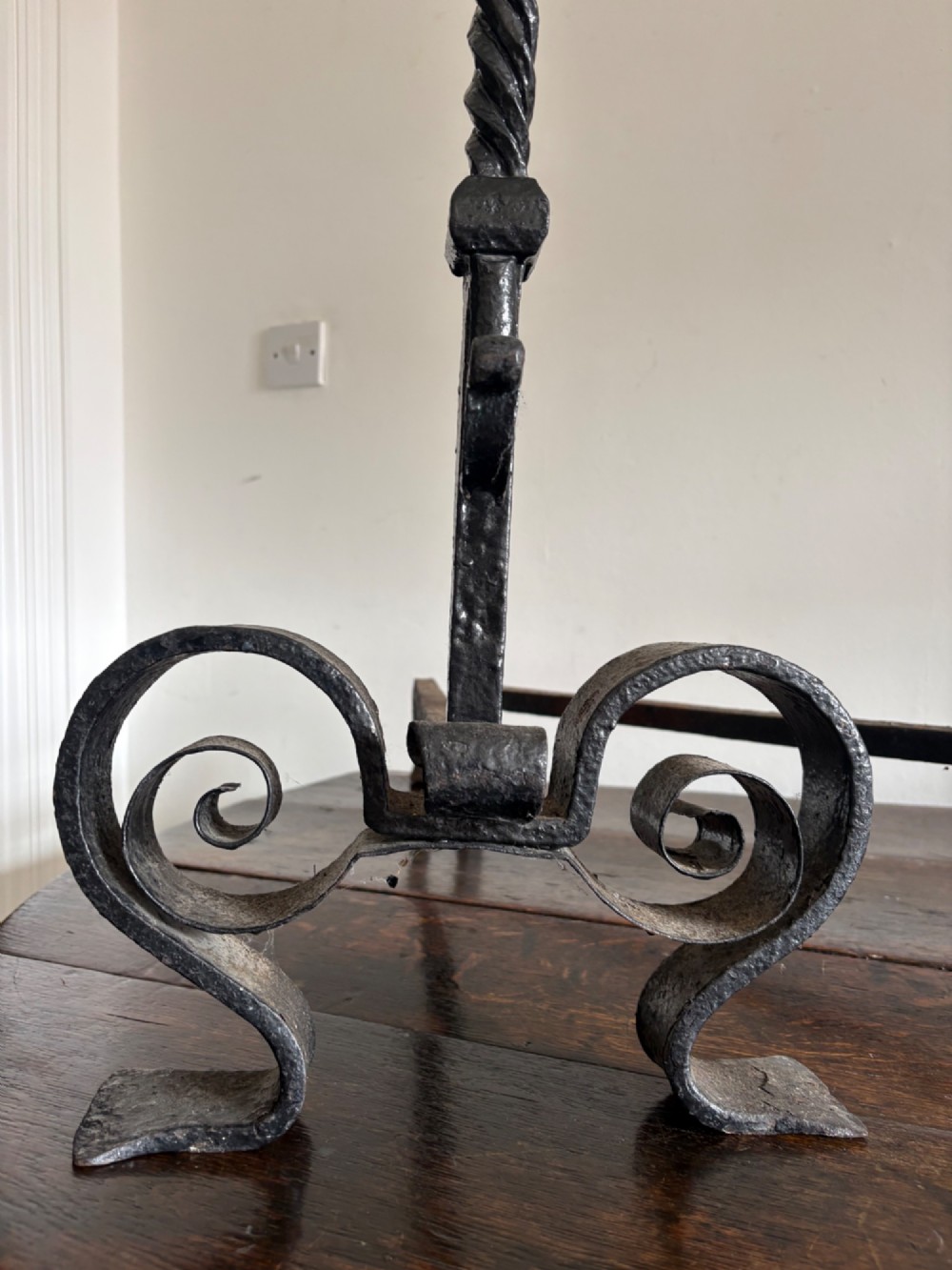 A pair of tall 19th-century black wrought iron fire dogs featuring hand-twisted shafts, scrollwork feet, and circular top ring terminals. View VII