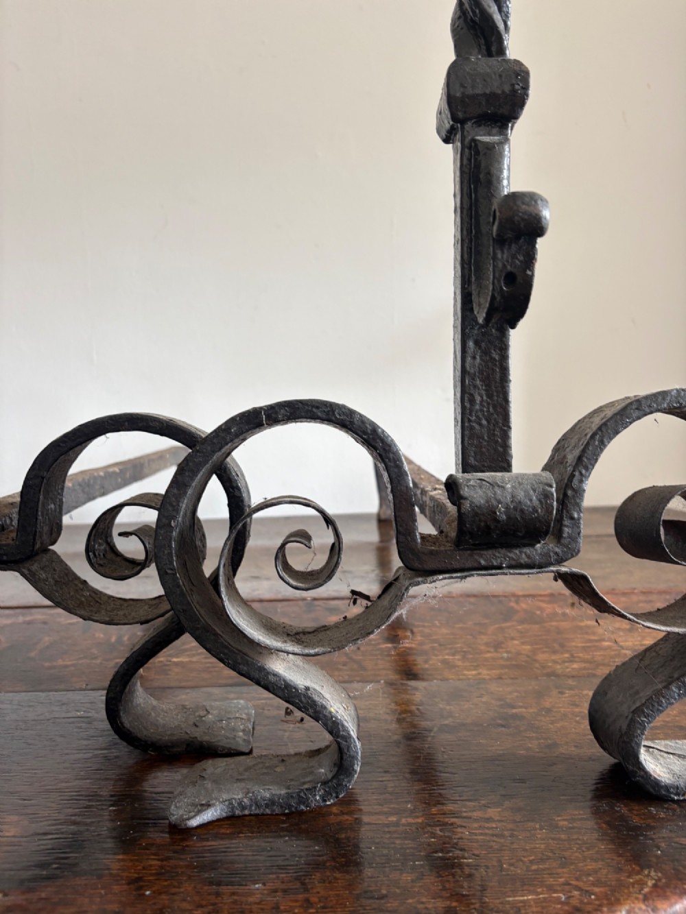 A pair of tall 19th-century black wrought iron fire dogs featuring hand-twisted shafts, scrollwork feet, and circular top ring terminals. View XI