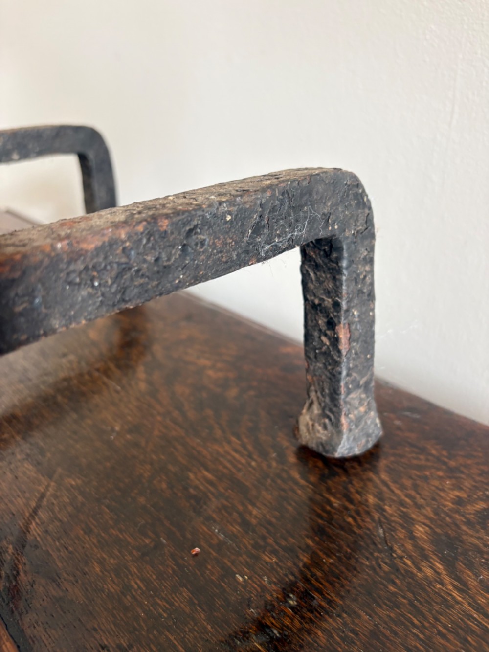 A pair of tall 19th-century black wrought iron fire dogs featuring hand-twisted shafts, scrollwork feet, and circular top ring terminals. View XV