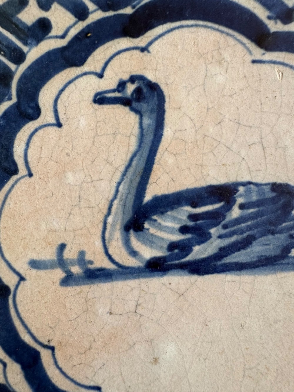 A square 17th-century tin-glazed earthenware tile featuring a hand-painted cobalt blue swan motif inside a scalloped border with geometric corner details. View III