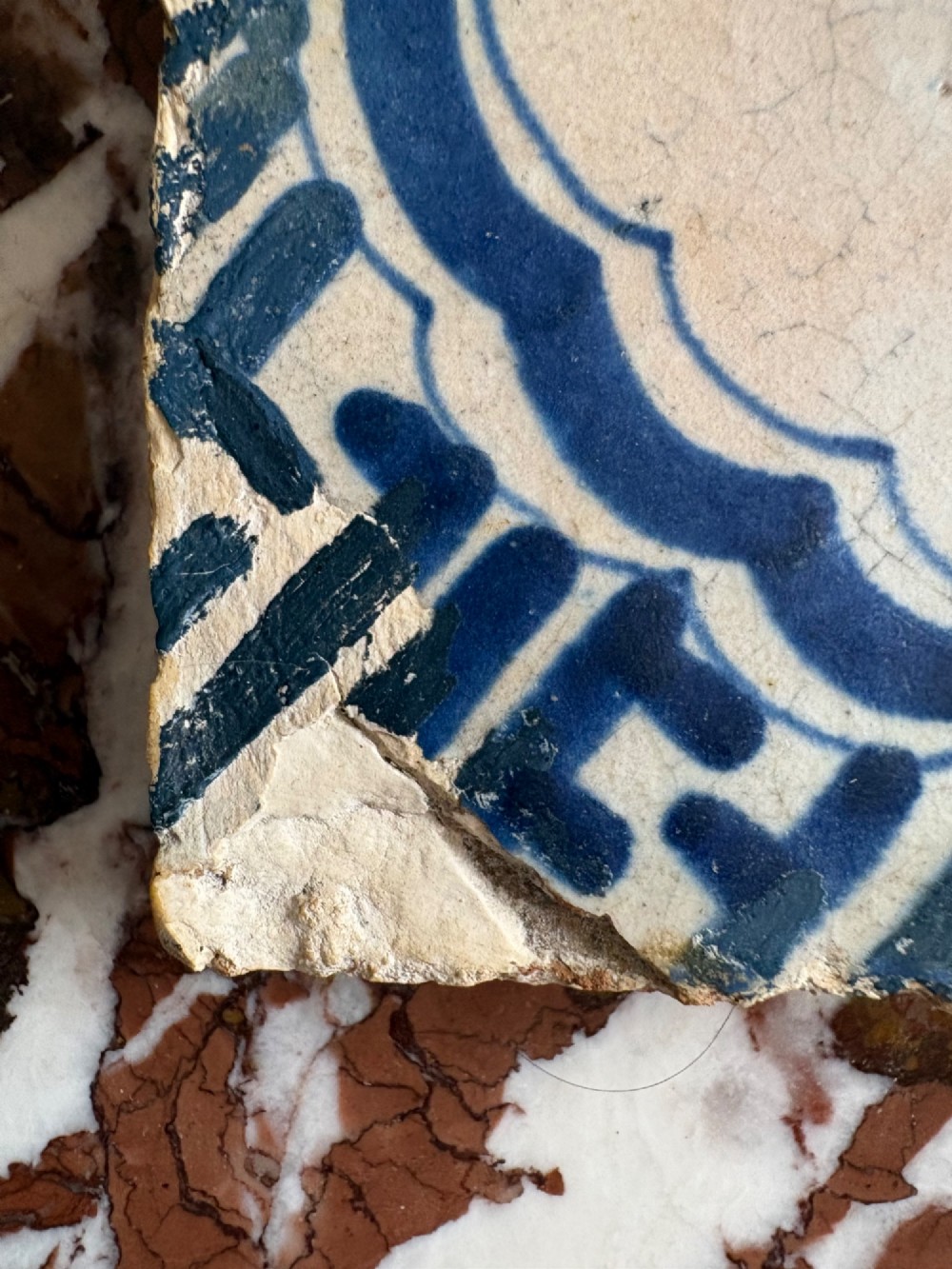A square 17th-century tin-glazed earthenware tile featuring a hand-painted cobalt blue swan motif inside a scalloped border with geometric corner details. View V