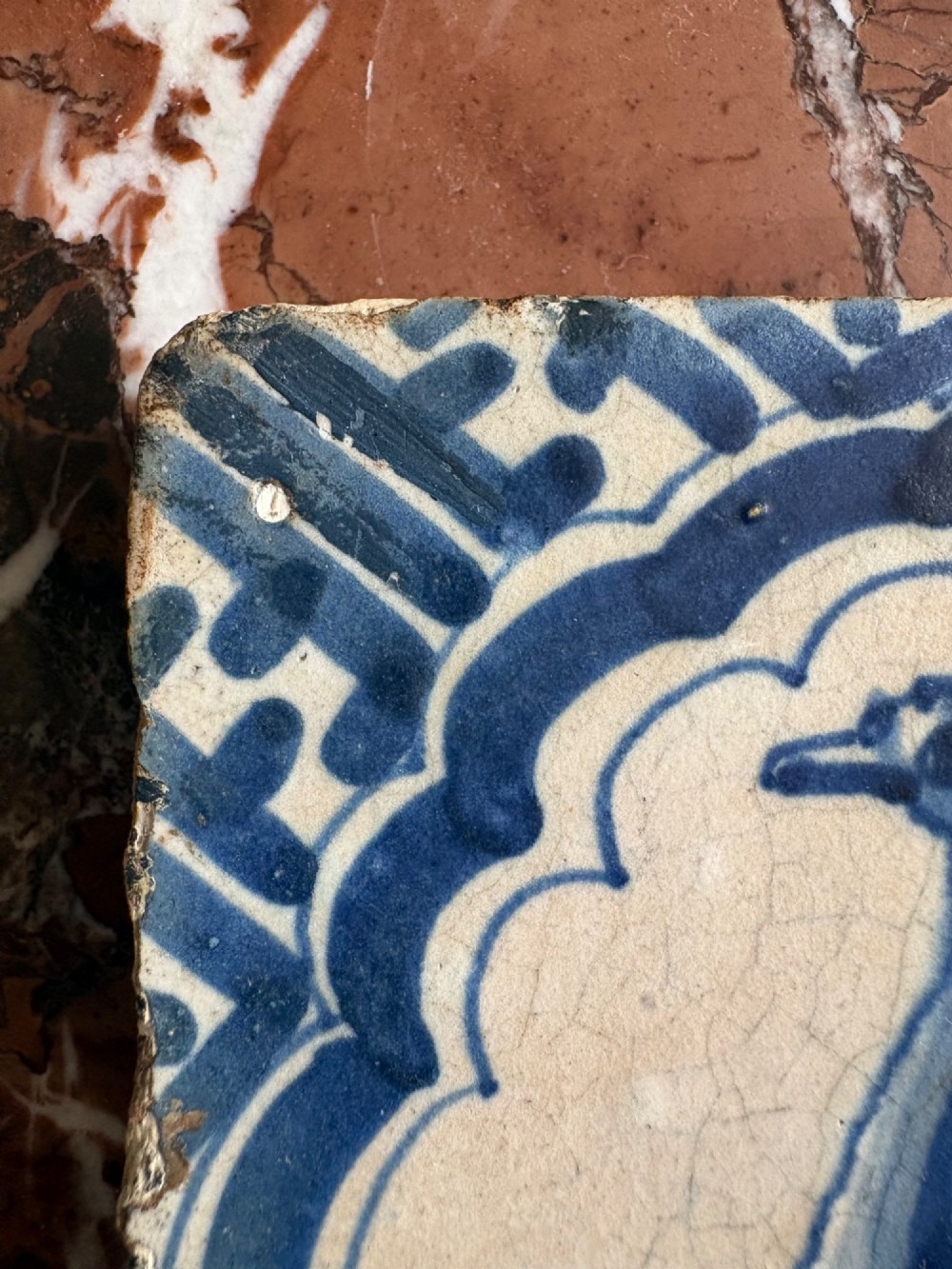 A square 17th-century tin-glazed earthenware tile featuring a hand-painted cobalt blue swan motif inside a scalloped border with geometric corner details. View VI